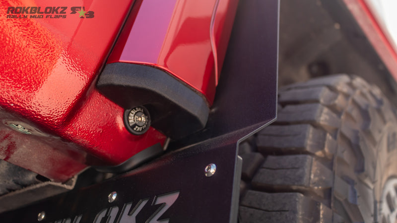 Detail of Rokblokz Step-Back Mud Flap fitment on GMC Sierra HD truck with oversized tires and factory fender flares.